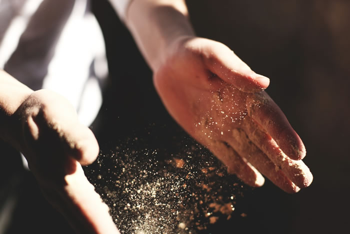 Dust floating between a person's hands. Photo by Austin Ban on Unsplash.