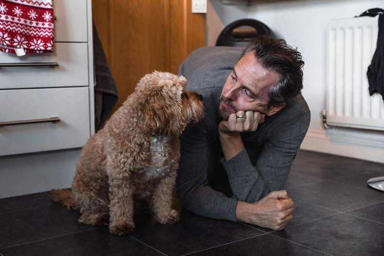 Man giving dog an "I'm very disappointed in you" look on tile floor. Photo by Charlie Green on Unsplash.