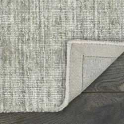 Custom-bound grey area rug with hand-serged edge and fabric backing